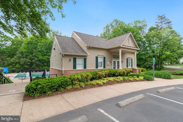 7820 Elsinore Dr, Manassas, VA 20112 - view of front of home with brick siding, a shingled roof, uncovered parking, and a fenced in pool