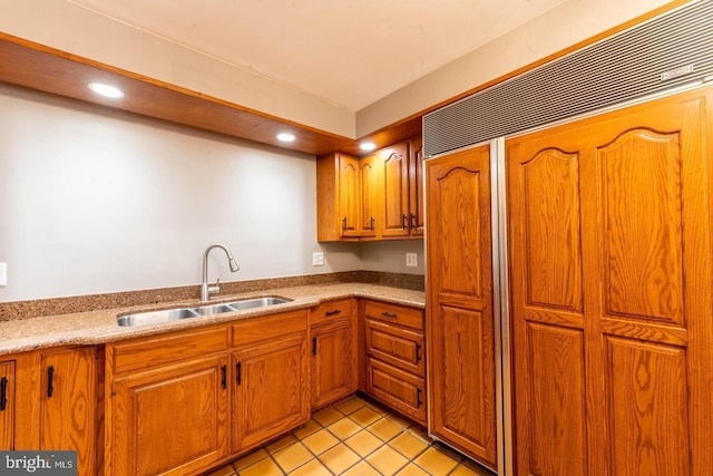 kitchen featuring brown cabinetry, a sink, and built in refrigerator