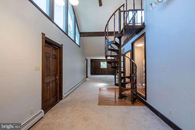 foyer with a baseboard heating unit, stairway, carpet floors, and a towering ceiling