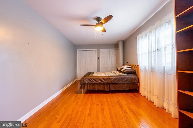 bedroom with ceiling fan, baseboards, light wood-style floors, and two closets