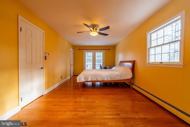 bedroom with baseboards, wood finished floors, a ceiling fan, and baseboard heating