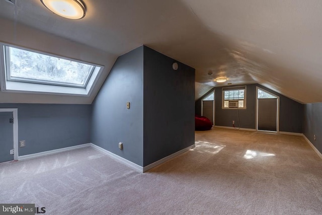 additional living space with carpet floors, lofted ceiling with skylight, and baseboards