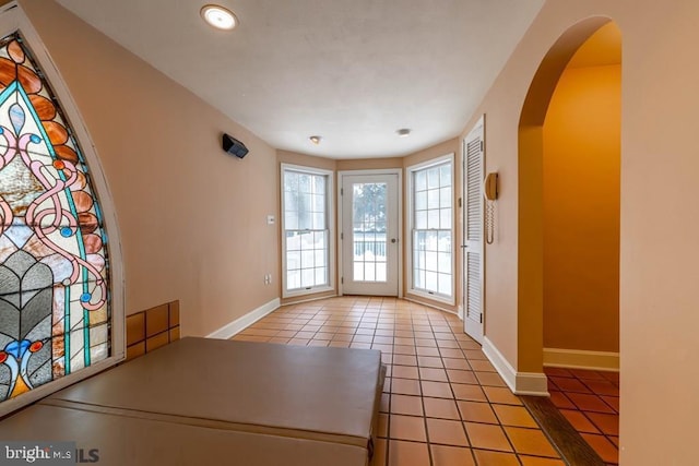 entryway featuring arched walkways, baseboards, recessed lighting, and light tile patterned floors