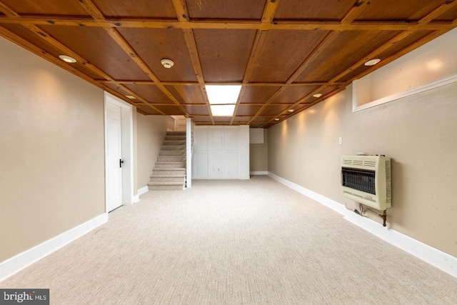 finished basement featuring heating unit, baseboards, stairs, and light colored carpet
