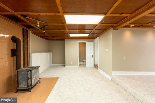 finished below grade area featuring light carpet and a wood stove