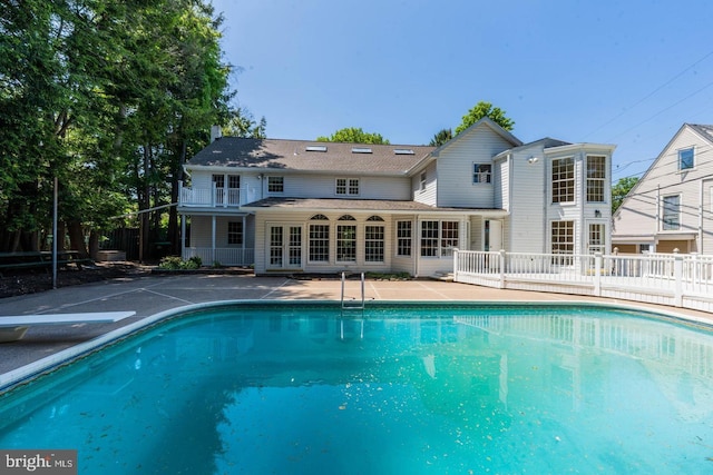view of swimming pool with a diving board, a patio, a fenced in pool, and french doors