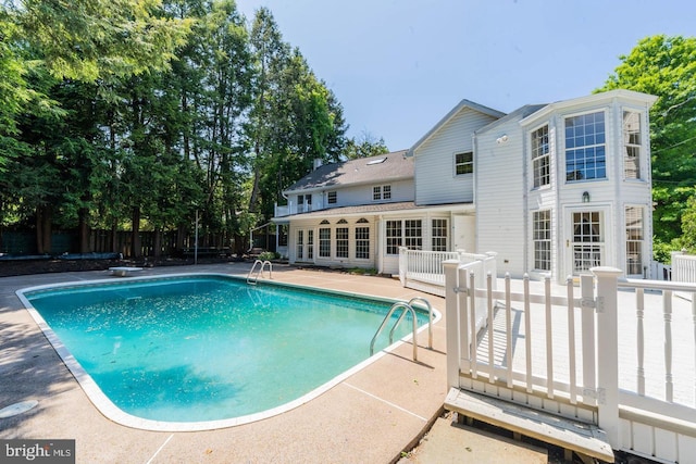 view of pool with fence, a patio area, a fenced in pool, and a diving board