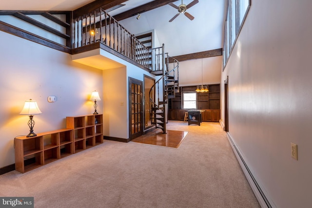 interior space with a high ceiling, a ceiling fan, baseboards, carpet flooring, and baseboard heating