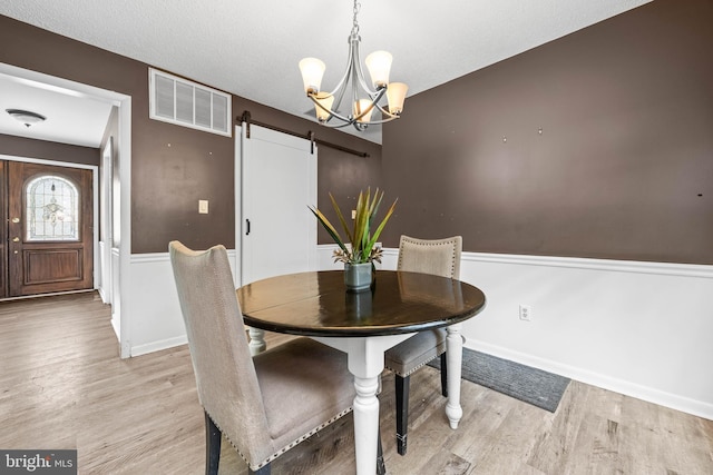 1713 Emerson Ave, Salisbury, MD 21801 - dining room featuring a barn door, light wood-style floors, a chandelier, and baseboards