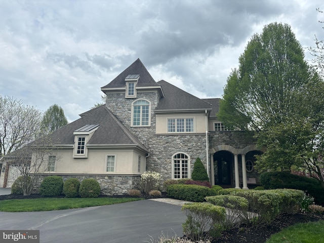 french country inspired facade featuring stone siding and stucco siding