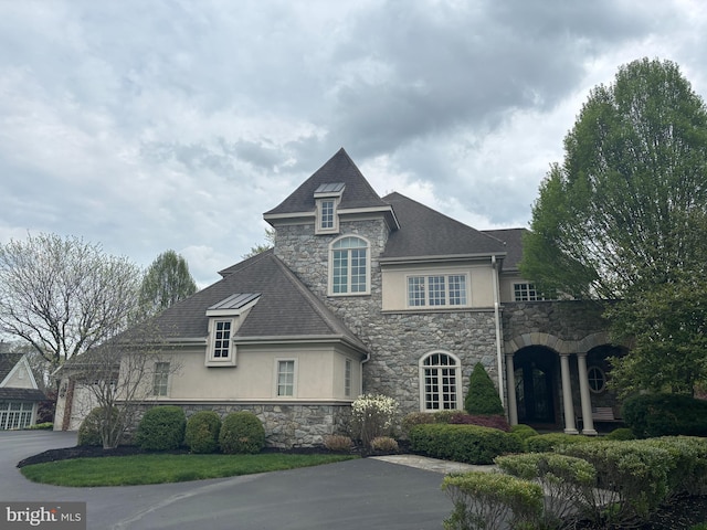 french country inspired facade featuring stucco siding and stone siding