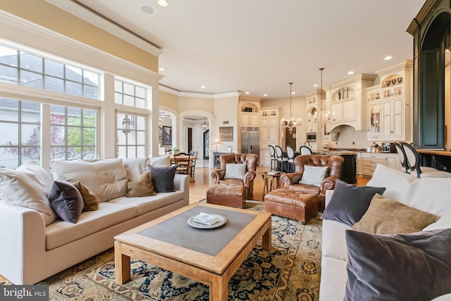living area featuring a chandelier, recessed lighting, ornamental molding, and arched walkways