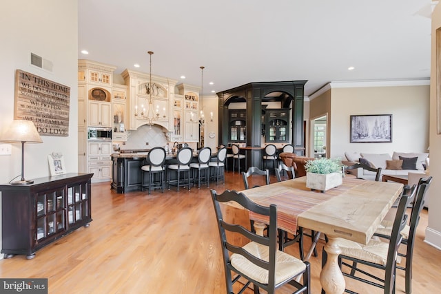 dining area with crown molding, recessed lighting, visible vents, and light wood-style flooring