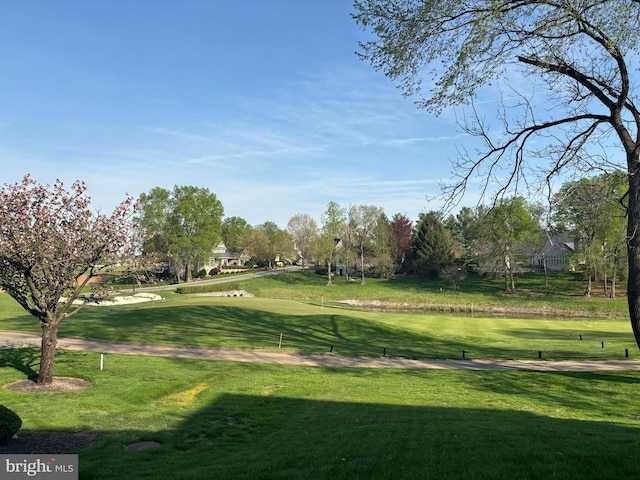 view of community featuring view of golf course and a lawn