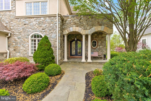 view of exterior entry featuring stone siding and stucco siding