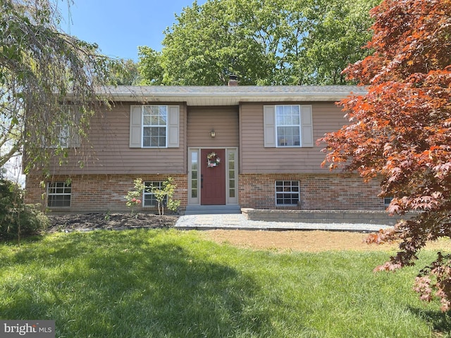 split foyer home with a chimney, a front yard, and brick siding