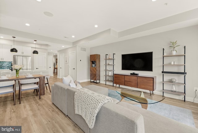 living room featuring recessed lighting, baseboards, and light wood-style floors