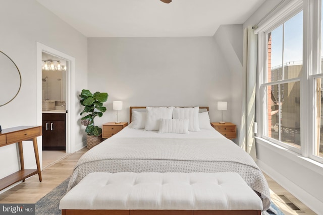 bedroom featuring visible vents, multiple windows, light wood-style flooring, and ensuite bathroom