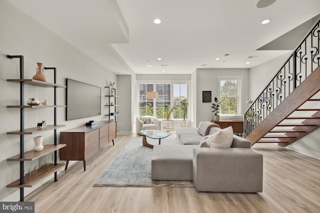 living area with recessed lighting, light wood finished floors, and stairs