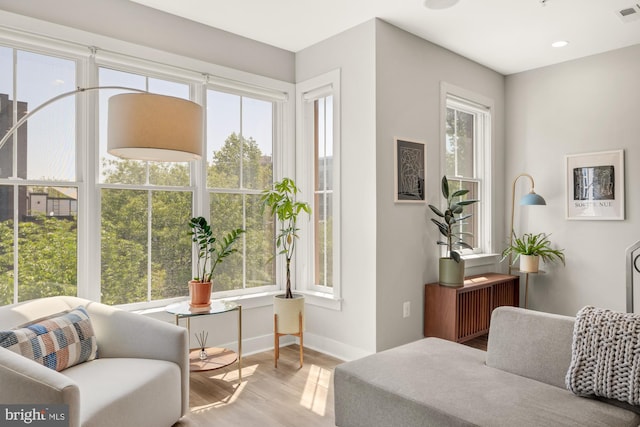 living area featuring baseboards, wood finished floors, a healthy amount of sunlight, and visible vents