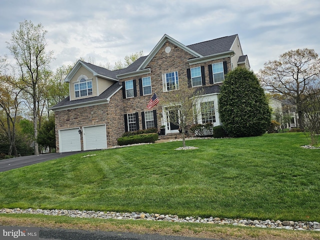 view of front of house featuring roof with shingles, a front lawn, aphalt driveway, a garage, and stone siding