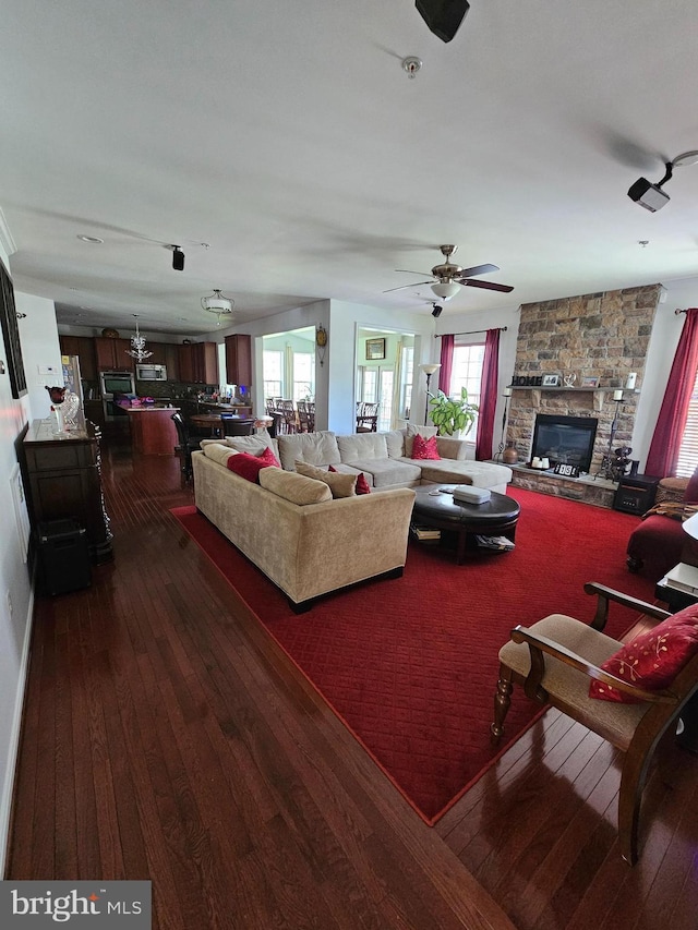 living room with plenty of natural light, a fireplace, and dark wood-style flooring