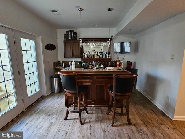 bar featuring visible vents, a dry bar, light wood-style flooring, and a healthy amount of sunlight
