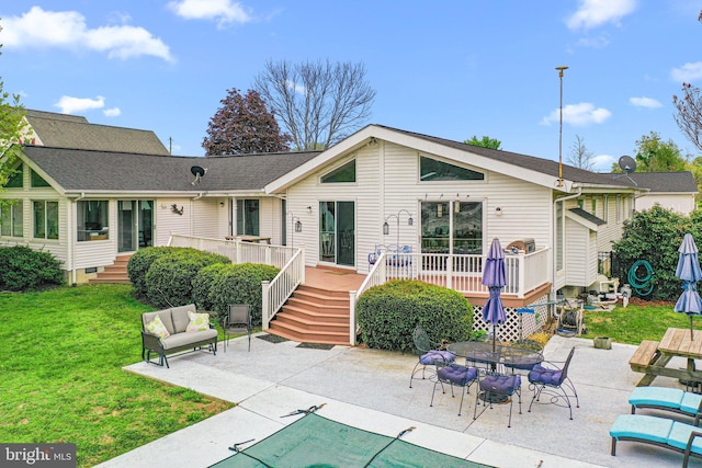 back of house featuring a deck, a patio, outdoor dining area, a shingled roof, and a lawn