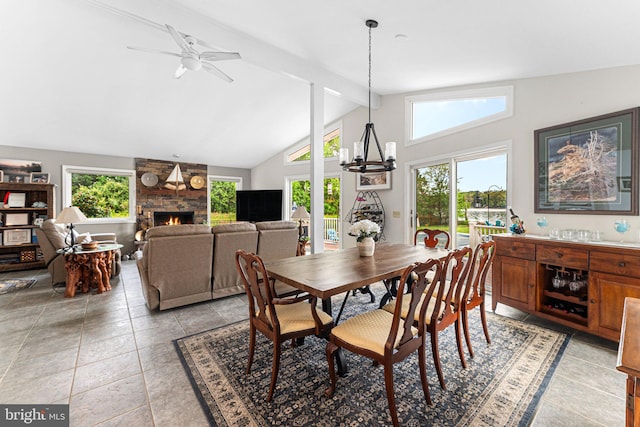 dining space with a fireplace, high vaulted ceiling, ceiling fan with notable chandelier, light tile patterned floors, and beamed ceiling