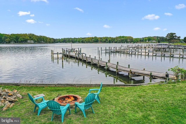 dock area with a water view, a fire pit, a yard, and boat lift