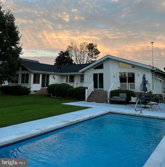 rear view of property featuring entry steps, a patio, a yard, and an outdoor pool