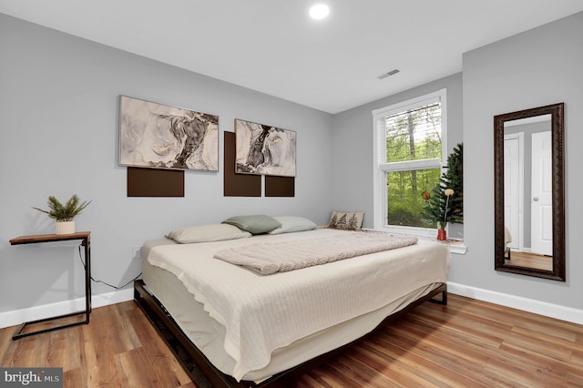 bedroom with baseboards, wood finished floors, and visible vents
