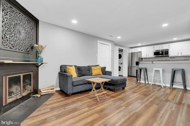 living area with recessed lighting, stacked washer and clothes dryer, and light wood finished floors