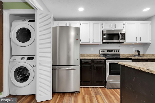 kitchen with stacked washing maching and dryer, white cabinets, stainless steel appliances, and recessed lighting