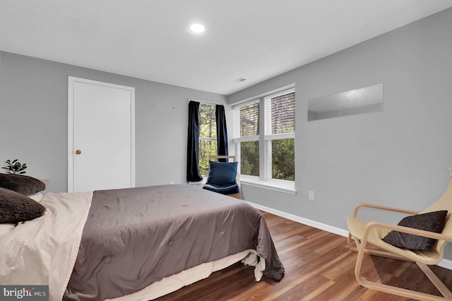 bedroom with baseboards, recessed lighting, wood finished floors, and visible vents