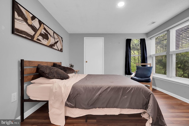 bedroom with baseboards, visible vents, and wood finished floors