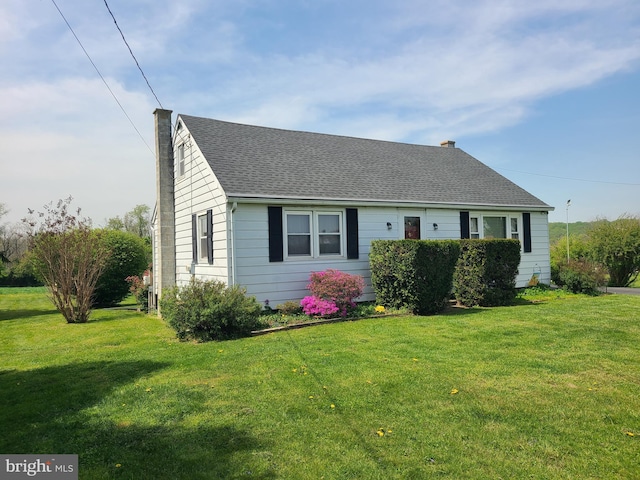 cape cod-style house with a chimney, roof with shingles, and a front yard
