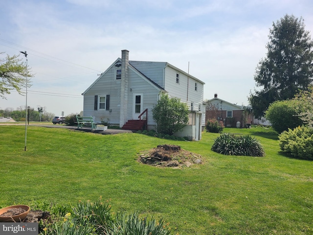 back of house with a chimney and a yard