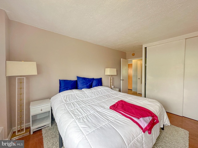 bedroom featuring a textured ceiling, wood finished floors, and a closet