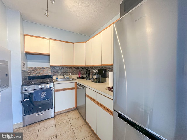 kitchen with a sink, appliances with stainless steel finishes, tasteful backsplash, and light countertops