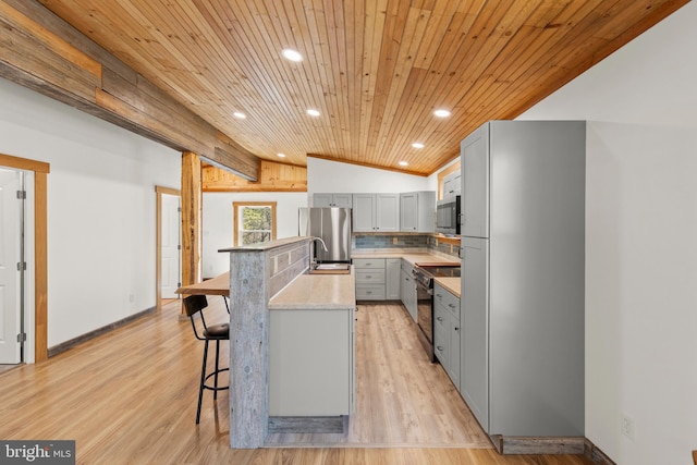 275 Oak Forest Ln, Berkeley Springs, WV 25411 - kitchen featuring recessed lighting, lofted ceiling, a kitchen breakfast bar, gray cabinets, and appliances with stainless steel finishes