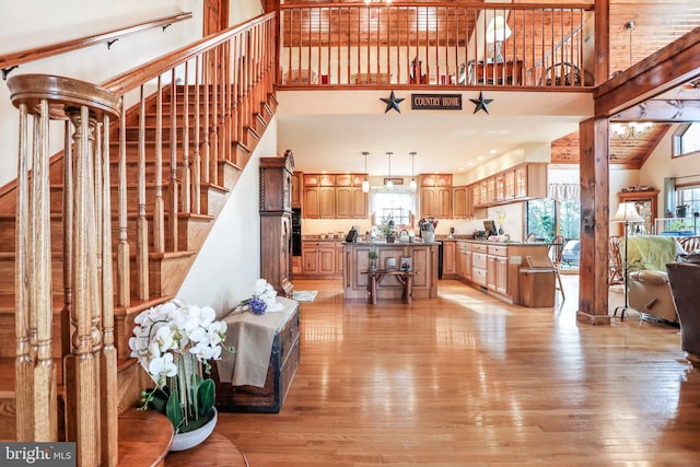 living area with light wood finished floors, a towering ceiling, and stairway