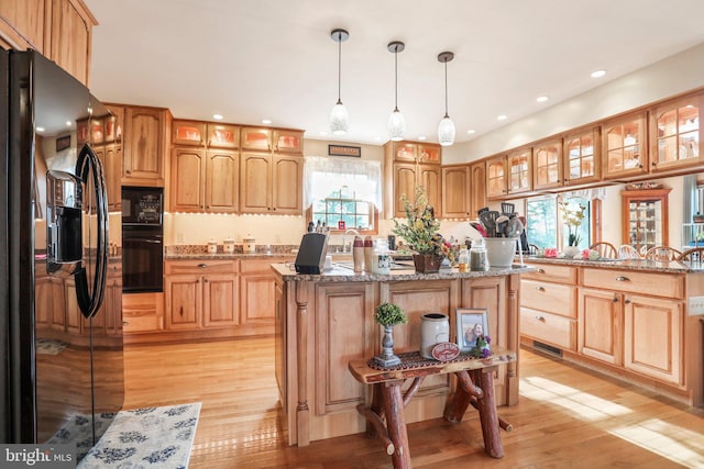 kitchen featuring recessed lighting, light stone countertops, black appliances, and light wood-type flooring