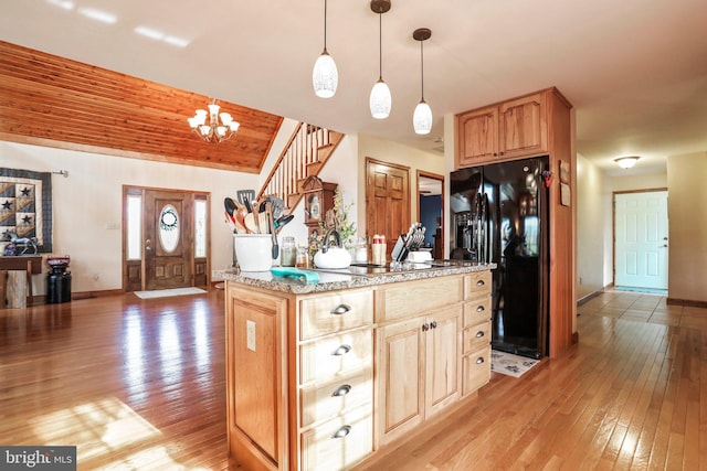 kitchen featuring a kitchen island, light wood-type flooring, baseboards, black appliances, and an inviting chandelier