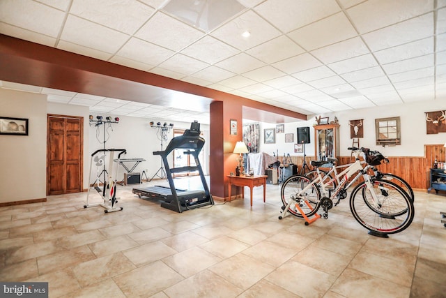 exercise room featuring tile patterned floors, wainscoting, and a paneled ceiling