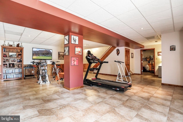 workout area featuring baseboards and a paneled ceiling