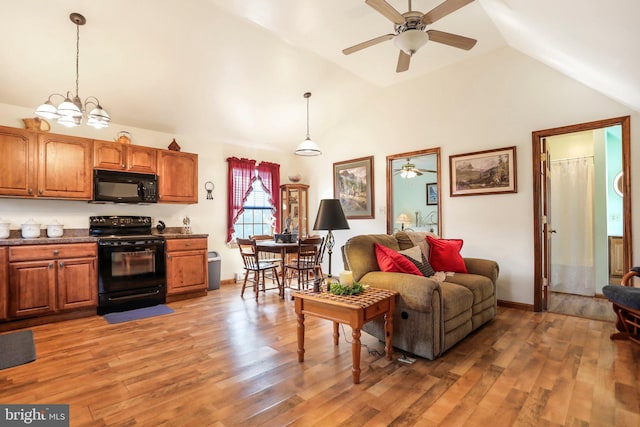 living area with light wood-style floors, a ceiling fan, and vaulted ceiling