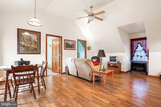 living room featuring baseboards, a ceiling fan, vaulted ceiling, and light wood finished floors