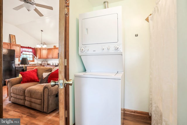 laundry area featuring laundry area, stacked washer and dryer, a ceiling fan, and wood finished floors