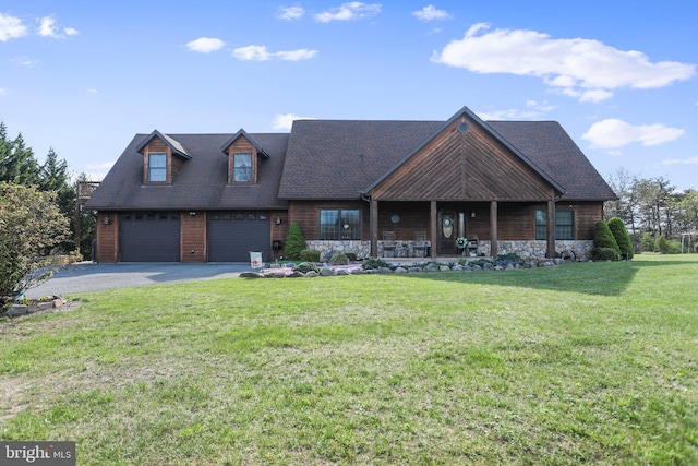 view of front of house featuring covered porch, aphalt driveway, a front lawn, an attached garage, and stone siding